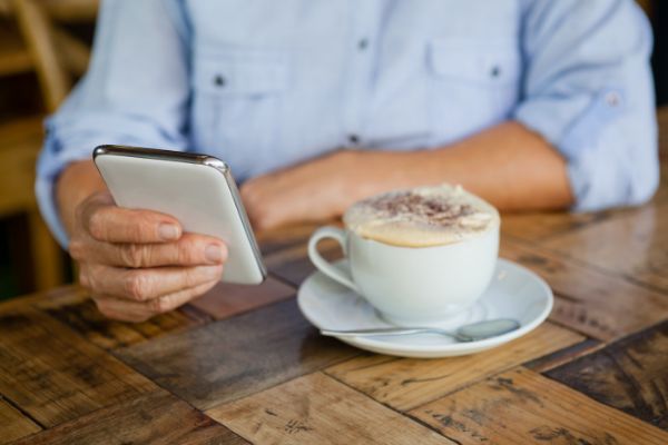 29446816_cropped-image-of-person-holding-smart-phone-while-sitting-by-coffee-cup (1)