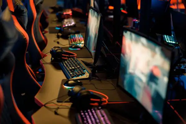 43703598 playing places with row of monitors, headsets and backlit colorful keyboards in dark gaming room