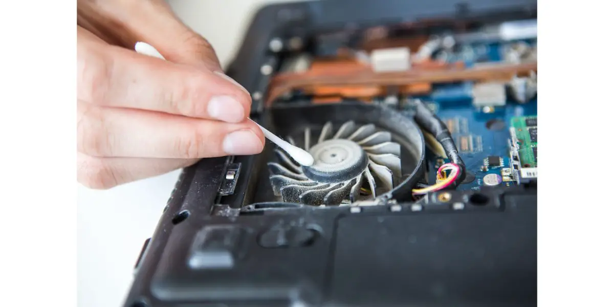 AdobeStock_111944365 man cleaning a opened up laptop and laptop fan with a soft q tip