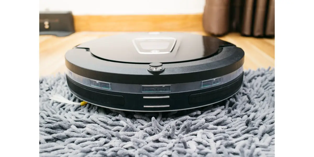 AdobeStock_118183871 Robot vacuum cleaner on laminate wood and carpet floor, Smart robotic automate wireless cleaning technology machine in living room.