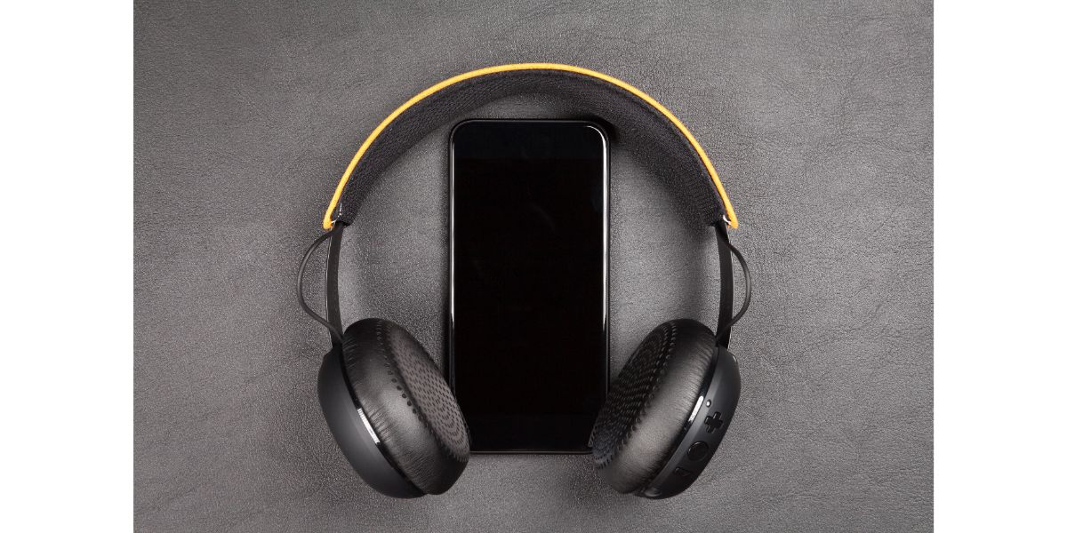 AdobeStock_127749069 Black modern smartphone and headphones on grey background