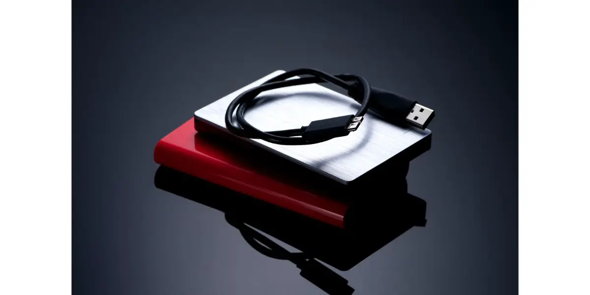 AdobeStock_129471094 stack of 2 external hard drives with usb cable on top omnious background