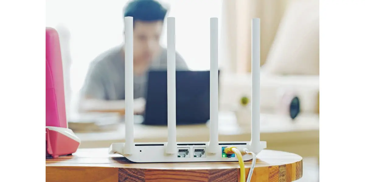 AdobeStock_142417254 closeup of a wireless router and a man using notebook on living room at home ofiice