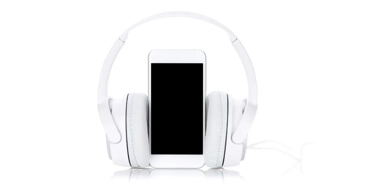 AdobeStock_150632104 Smartphone with headphones over them on white background