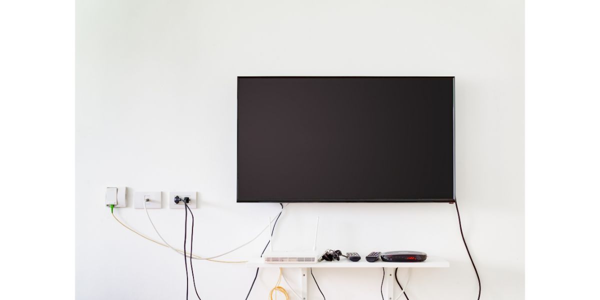 AdobeStock_160583926 lcd tv on wall with remote, wireless internet access point and set top box