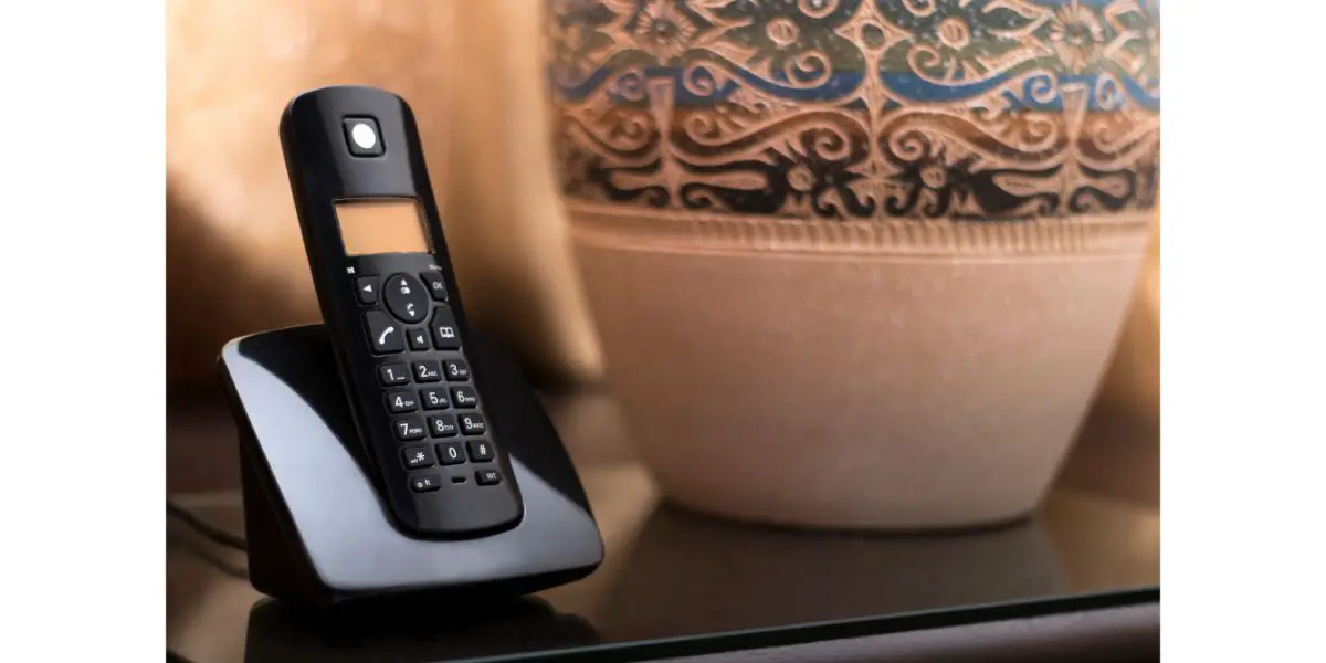 AdobeStock_160674561 cordless Telephone at hotel room sitting on bedside table with the table lamp.