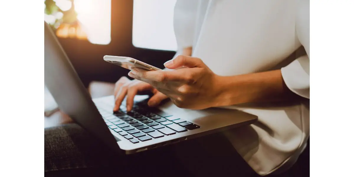 AdobeStock_160849901Soft focus of woman hand working with phone on desk in coffee shop