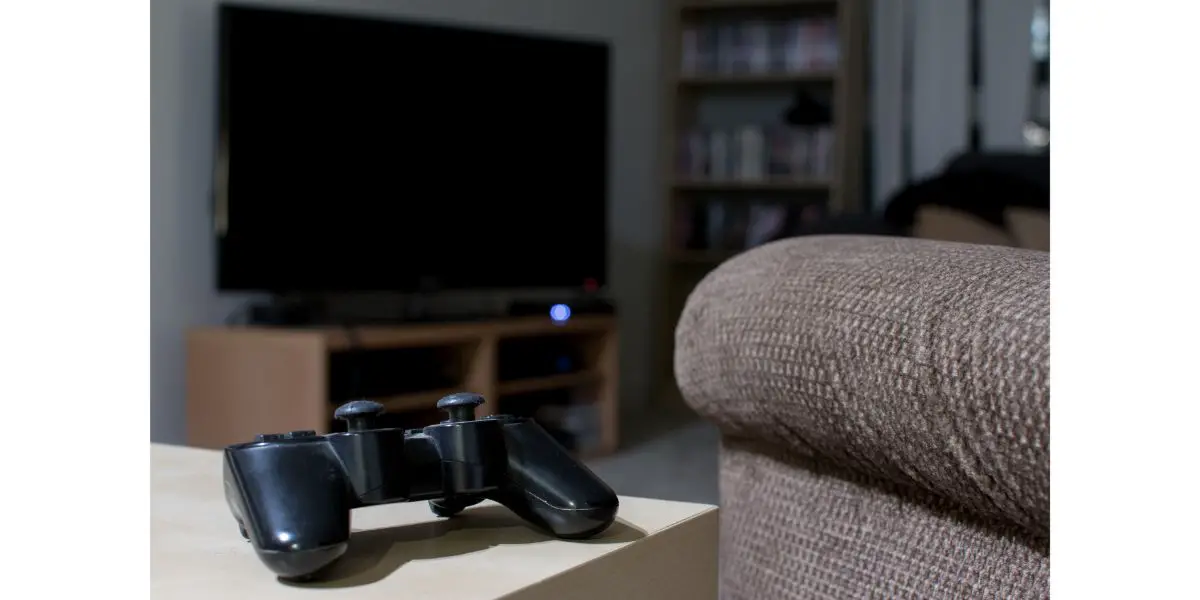 AdobeStock_173855306 ps3 controller on top of wooden table next to couch in living room waiting for TV to be turned on