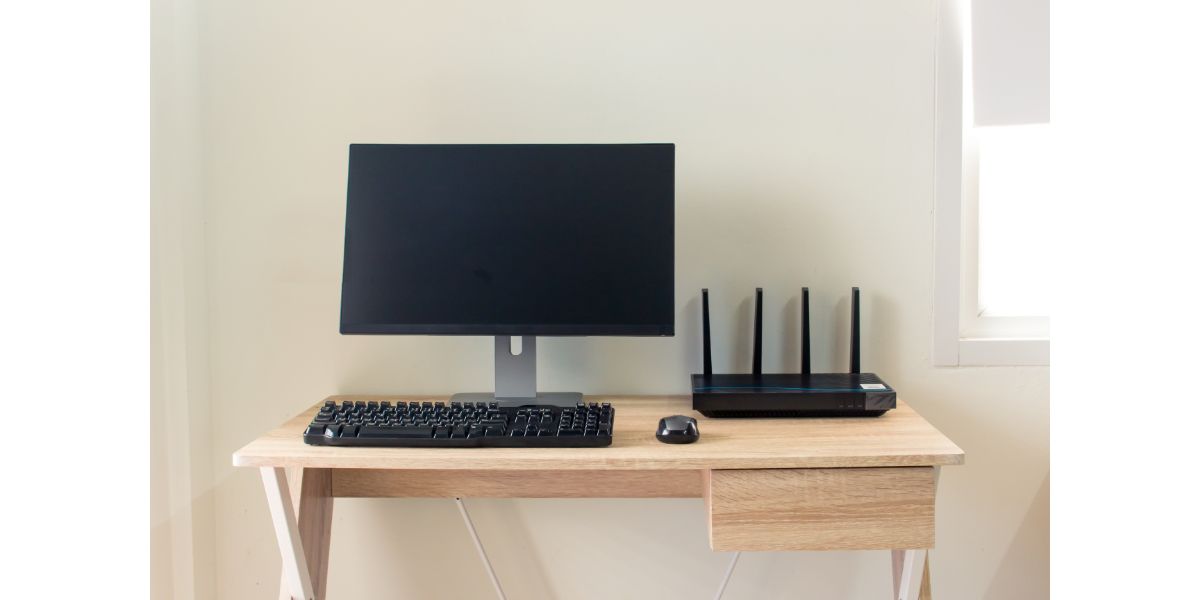 AdobeStock_174146685 Office table with wifi router and computer and supplies