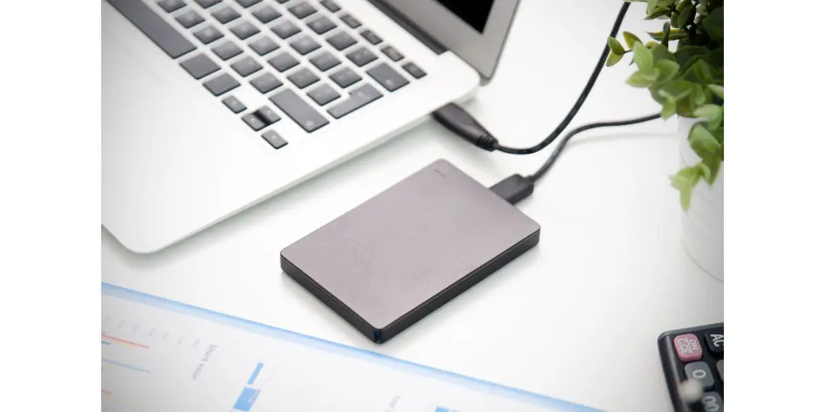 AdobeStock_175778089 External backup disk hard drive connected to laptop