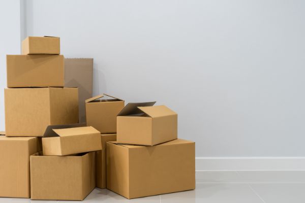 AdobeStock_184053373 Stack of cardboard boxes in empty room