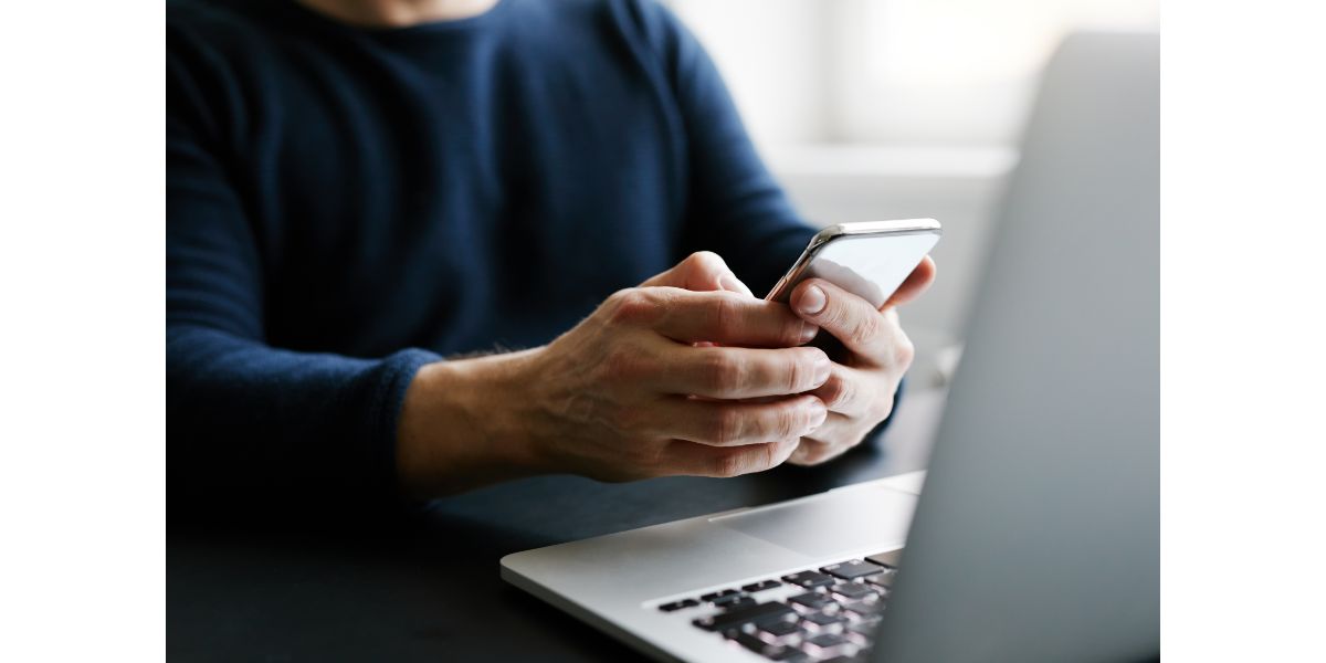 AdobeStock_188717574 Man with mobile phone and laptop in office