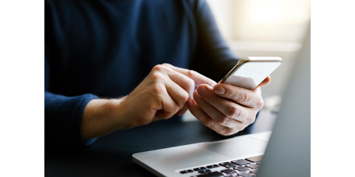 AdobeStock_188717596 Man with a finger on the screen using a mobile phone in the office