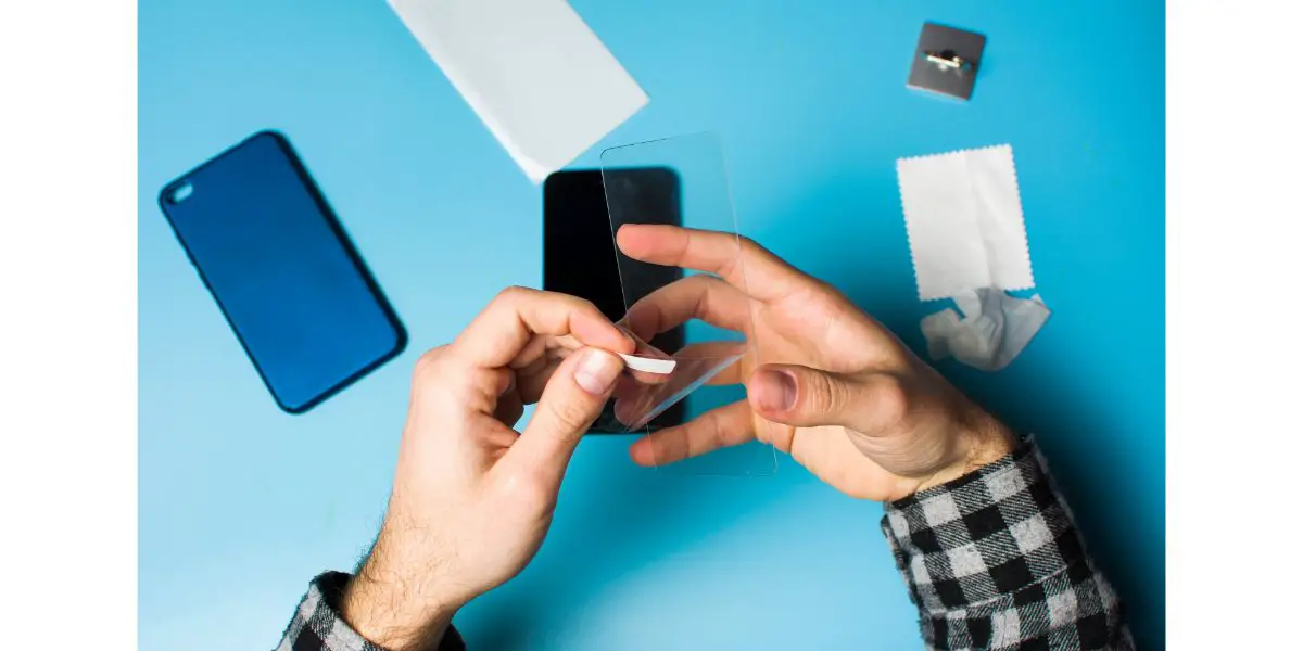 AdobeStock_193182013 Man applying protective tempered glass to phone screen