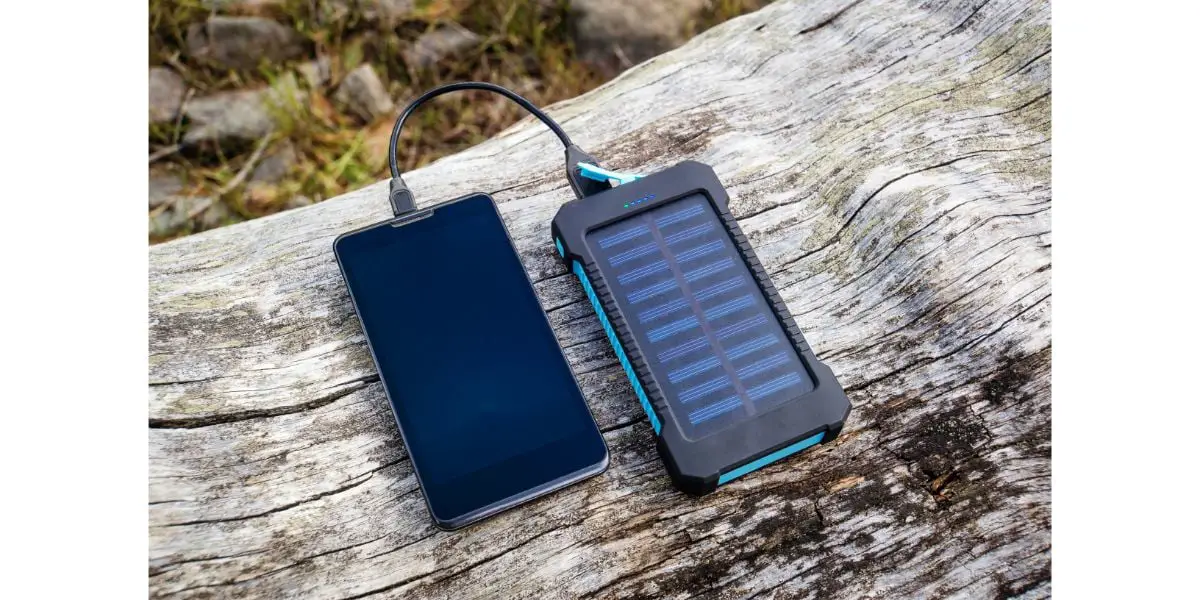 AdobeStock_195734829 Smartphone charging with solar power bank on wood background