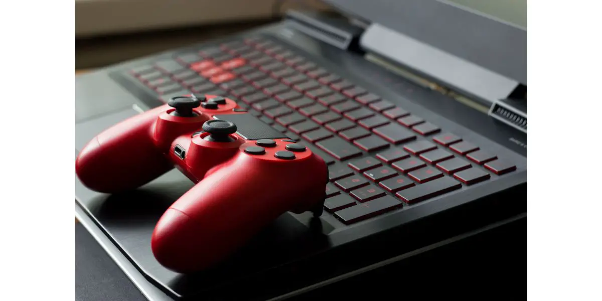 AdobeStock_204287716 Side view on black gaming laptop computer keyboard and modern red gamepad. Gaming concept