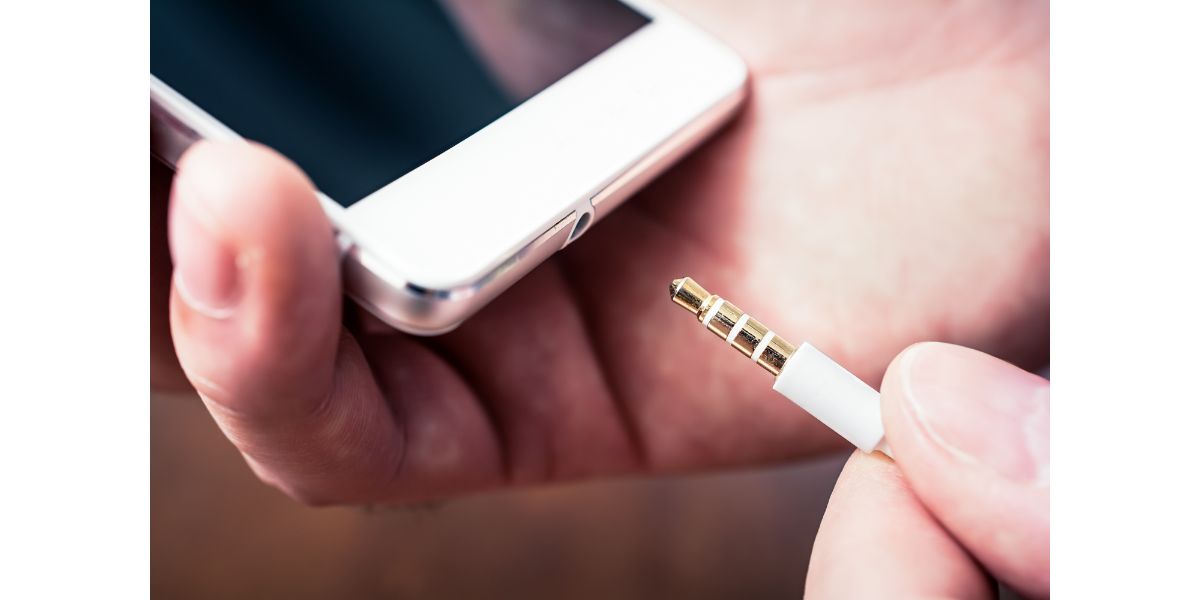 AdobeStock_210581629 Headphone Jack Of A White Smartphone Gets Plugged In A White Headset Cable