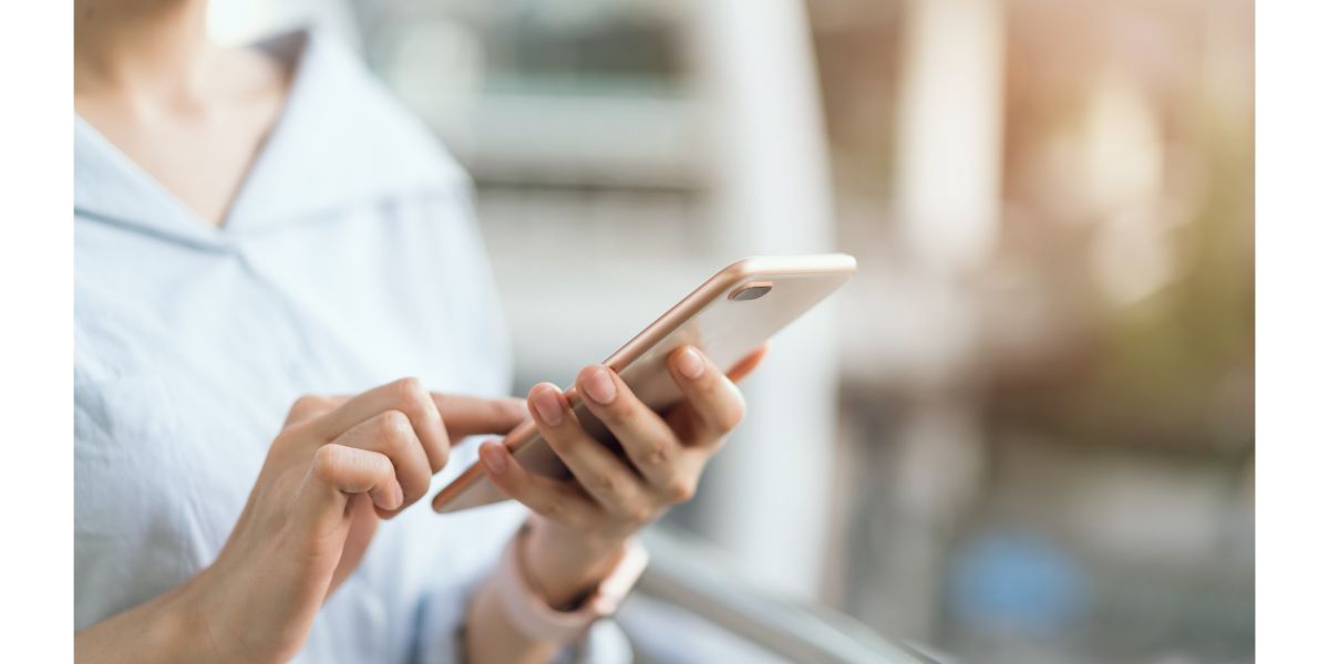 AdobeStock_215665703 woman using smartphone on staircase in public areas, During leisure time.