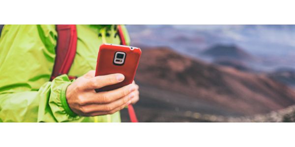 AdobeStock_215708380 Mobile phone man using his cellphone texting a text message during hiking