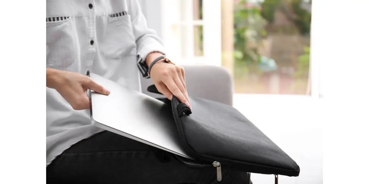 AdobeStock_224258701 Woman putting laptop into case indoors, closeup