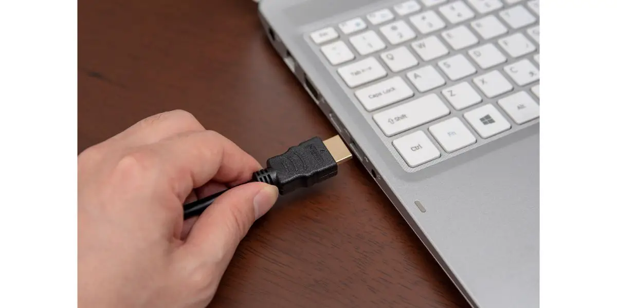 AdobeStock_225633992 Man is connecting black hdmi cable into laptop