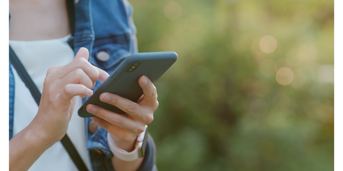 AdobeStock_230871763 Woman use of mobile phone over sunlgiht