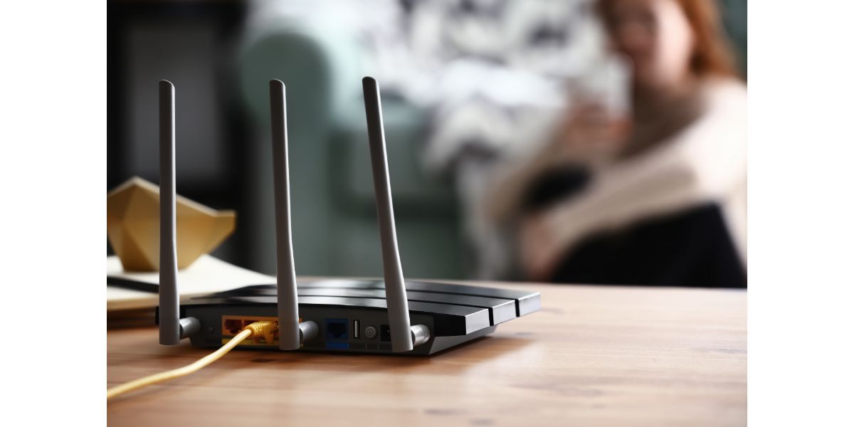 AdobeStock_239323943 Modern wi-fi router on wooden table in room