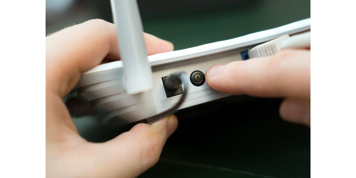 AdobeStock_244514531 Man pressing power button on the wifi router