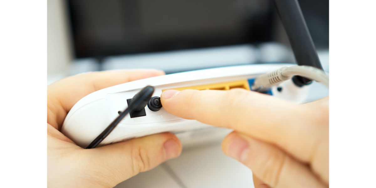 AdobeStock_244514846 Man pressing power button on the wifi router. Blurred background