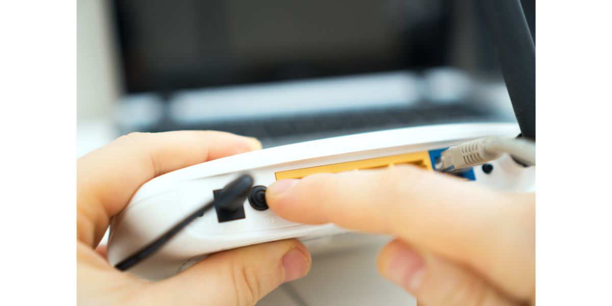 AdobeStock_244514866 Man pressing power button on the wifi router