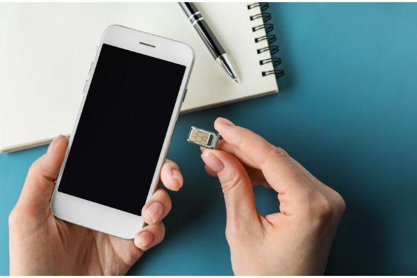 AdobeStock_248000432 Woman inserting sim card into mobile phone, closeup