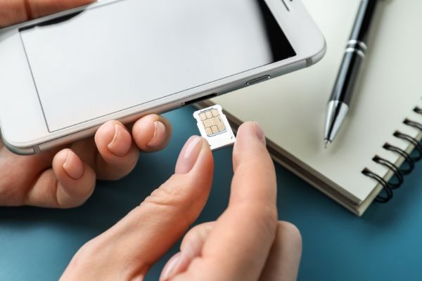 AdobeStock_248000433 Woman inserting sim card into mobile phone