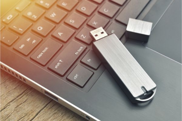 AdobeStock_255460854 Close up of metal USB flash drive connected to laptop on wood desk