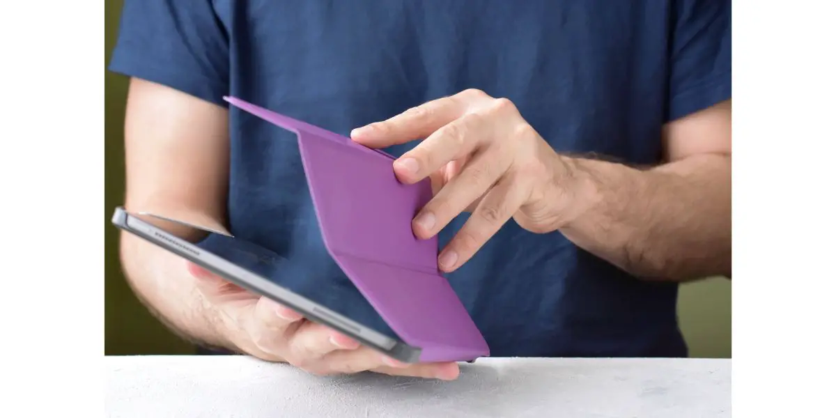 AdobeStock_256166692 Blurred caucasian man using a digital tablet. White man taking off purple leather case on tablet with selective focus