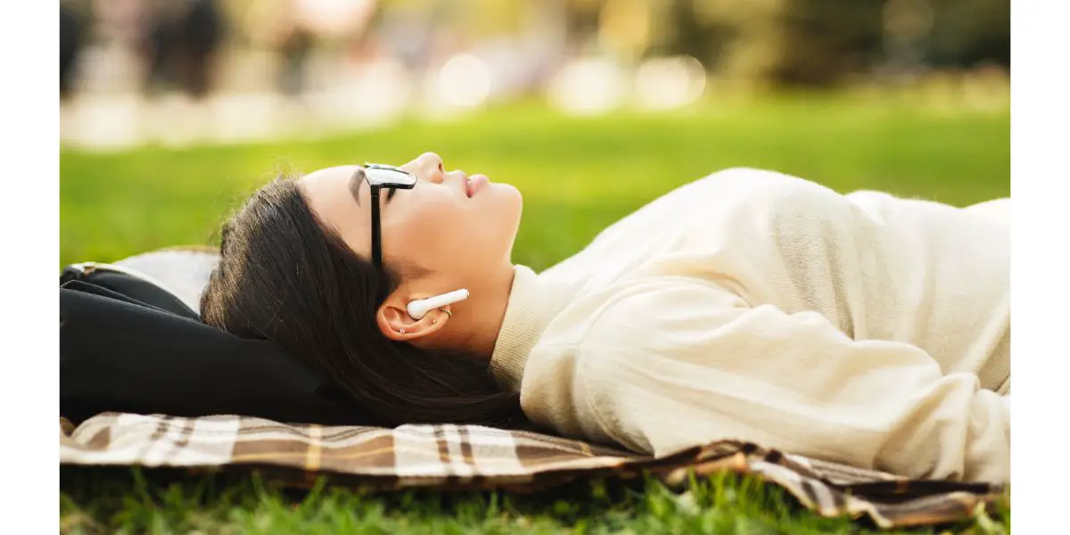 AdobeStock_278503119 Girl listening music in airpods, lying on blanket