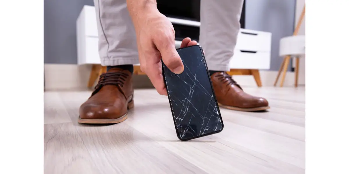 AdobeStock_280656376 Man Picking Up Damaged Mobile Phone