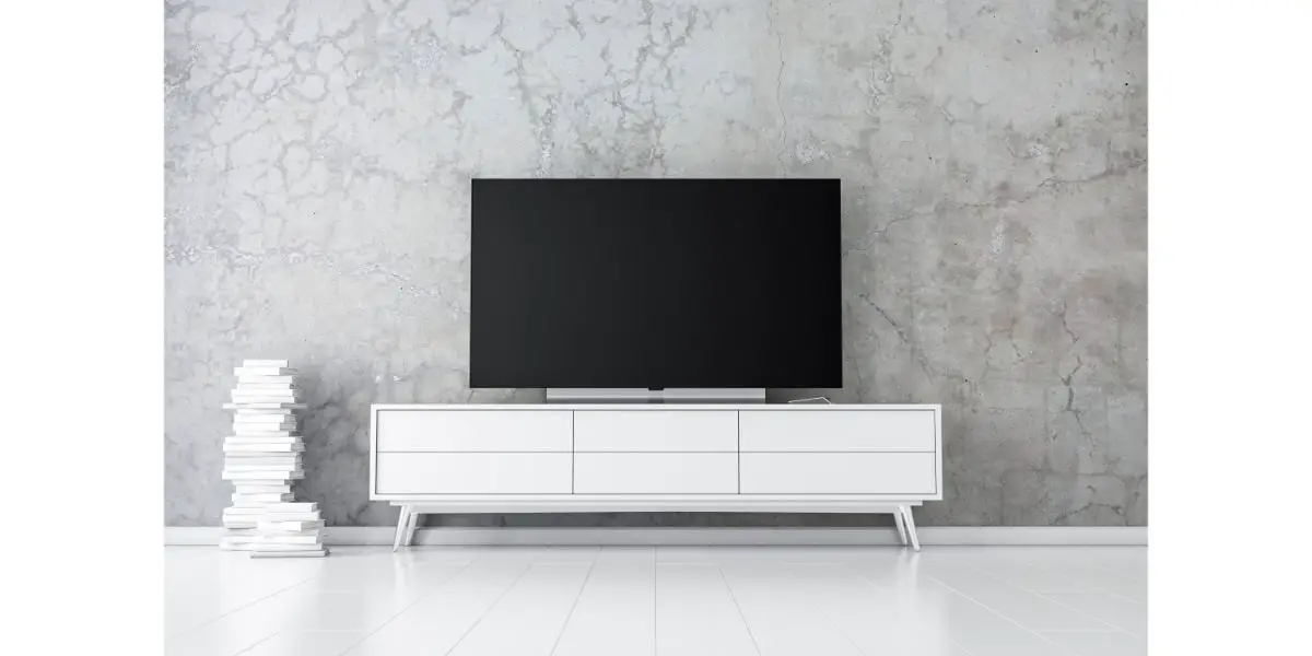 AdobeStock_281621332 Large Smart Tv Mockup on tv stand next to books with concrete background