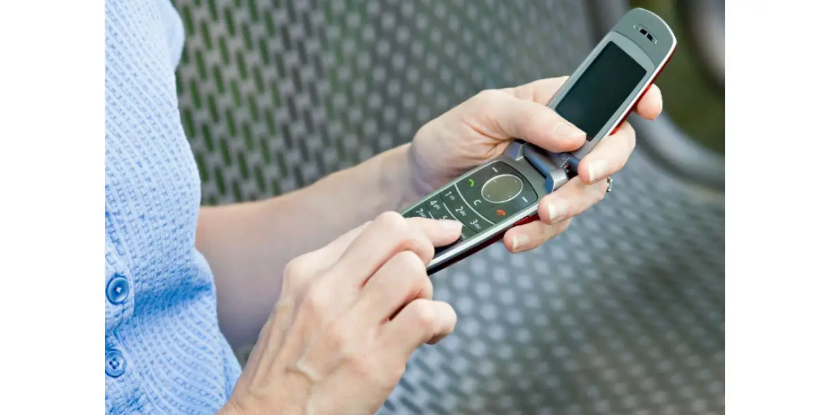 AdobeStock_28297954 woman using a flip phone pushing some keys