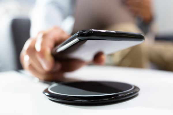 AdobeStock_286939212 Man Charging Smartphone Using Wireless Charging Pad