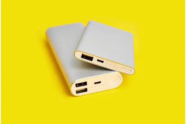 AdobeStock_290309051 White smart phone charger with power bank. Battery bank on a yellow background