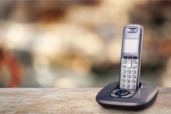 AdobeStock_293577640 Cordless phone with cradle on white background