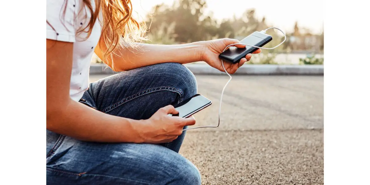 AdobeStock_309011098 woman hands holding black smartphone charging battery from external power bank