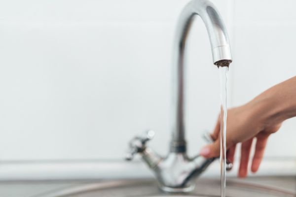 AdobeStock_310865199 woman hand opening silver faucet or water tap with metal washing sink in the kitchen