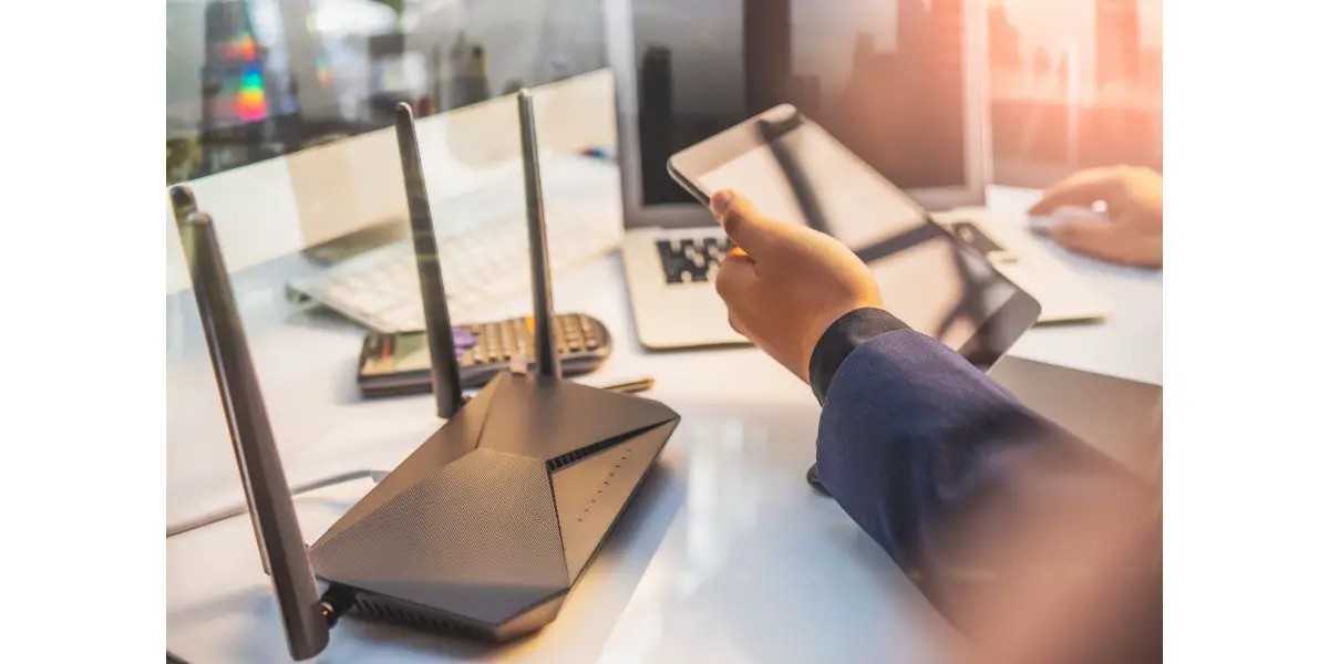 AdobeStock_315375338 Dual Band Router or Wireless AC router with business man using a computer and tablet in home office background .