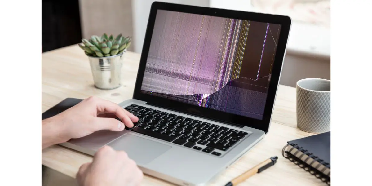 AdobeStock_315562354 Man working with a broken laptop computer on office business background