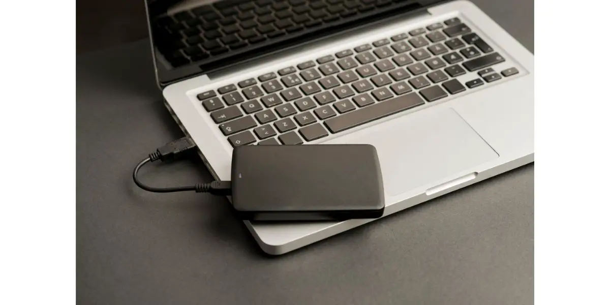 AdobeStock_321154741 external hard drive black on laptop, on office table, black