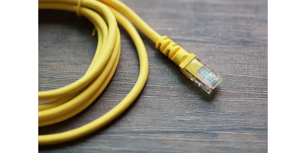 AdobeStock_329143989 yellow ethernet cable coiled up on wood background