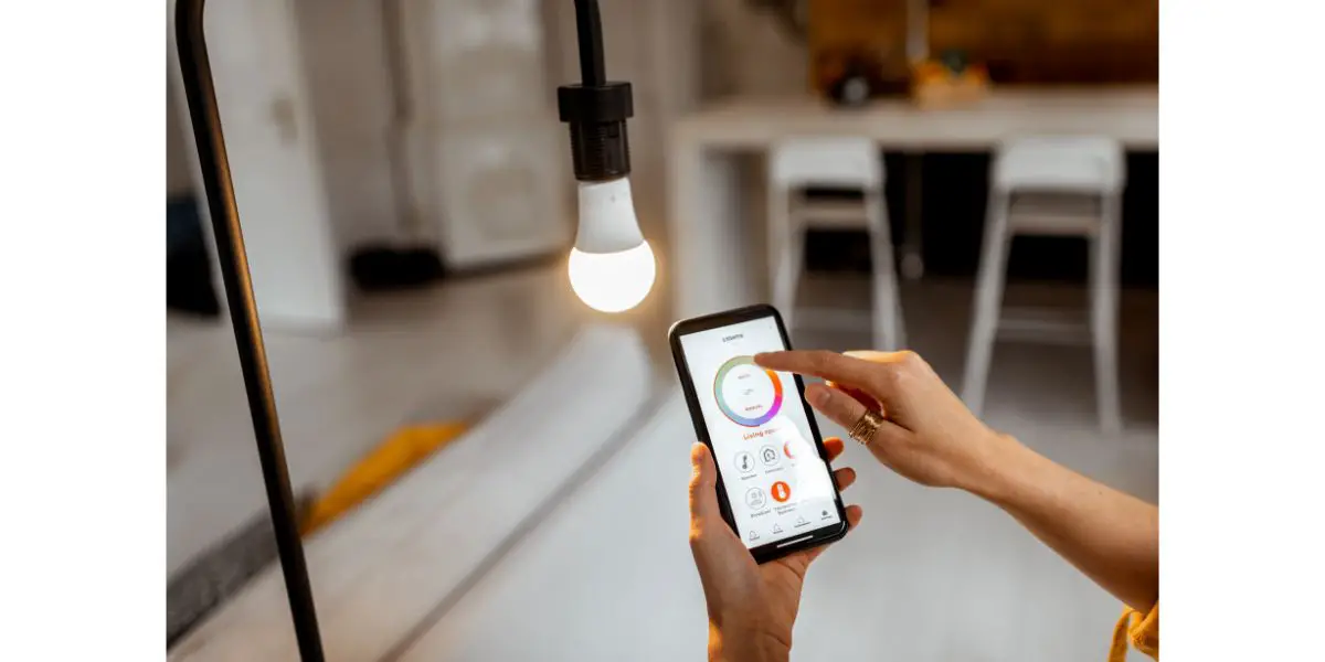 AdobeStock_329551679 Controlling light bulb temperature and intensity with a smartphone application. Concept of a smart home and managing light with mobile devices