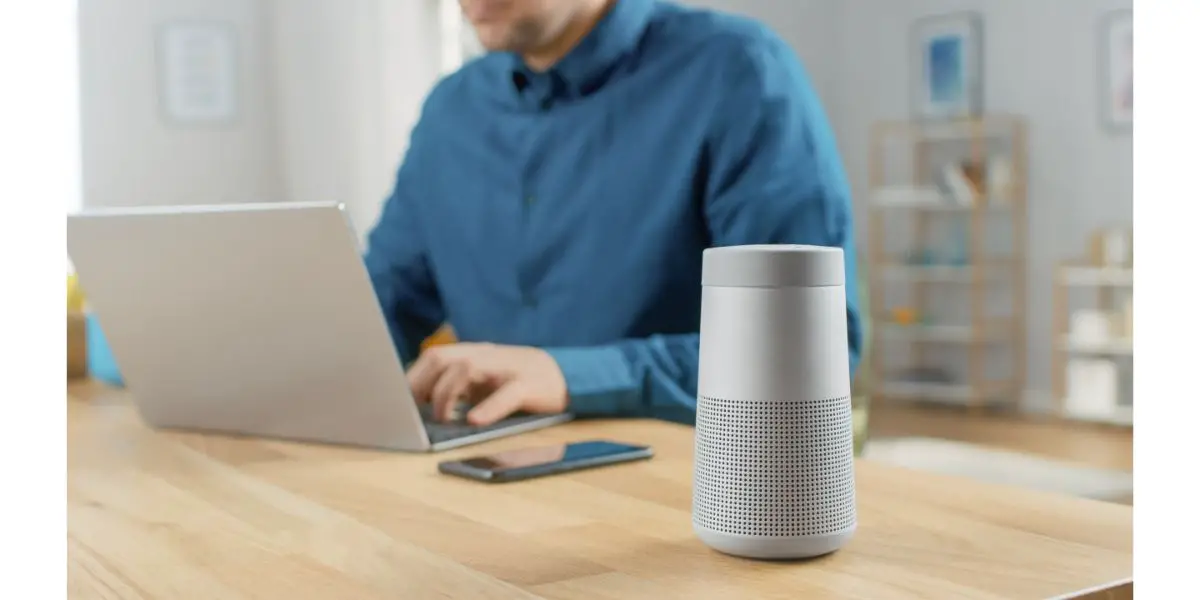 AdobeStock_330372192 Close Up Shot of a Modern Silver Bluetooth Speaker Standing on a Table at Home