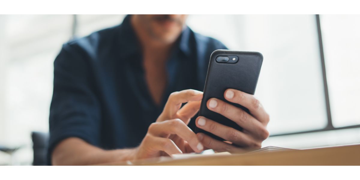 AdobeStock_336084017 close up of a man holding a smartphone in an office space